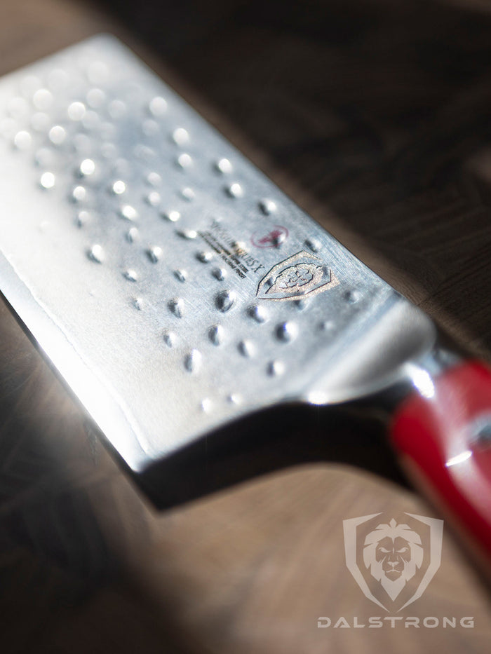 Dalstrong shogun series 6 inch nakiri knife with crimson red handle shined directly by the light on a wooden board.